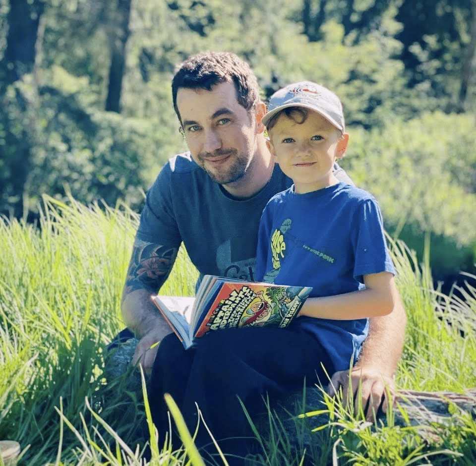 Dharma Dog founder, Nik Fabisiak, with his son reading a book